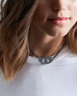 A close up of a model in a white t-shirt wearing the Cuban style handcuff chain