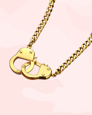 Gold handcuff necklace on a pink background