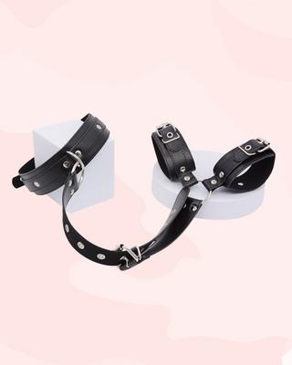 Black leather wrist cuffs on a white stand with a pink background