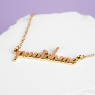 Close-up of the 'Punish Me' engraving on the gold pendant, showing fine details