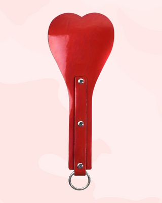 Red heart-shaped paddle with a o-ring on a light pink background