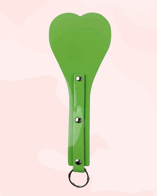 Green paddle with a keychain on a light pink background