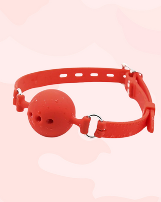 The red Velvet Bite ball gag shown with water droplets on, it is waterproof.