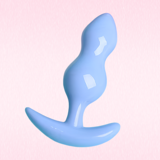 A glossy light blue silicone butt plug with a curved base, shown against a soft pink textured background.