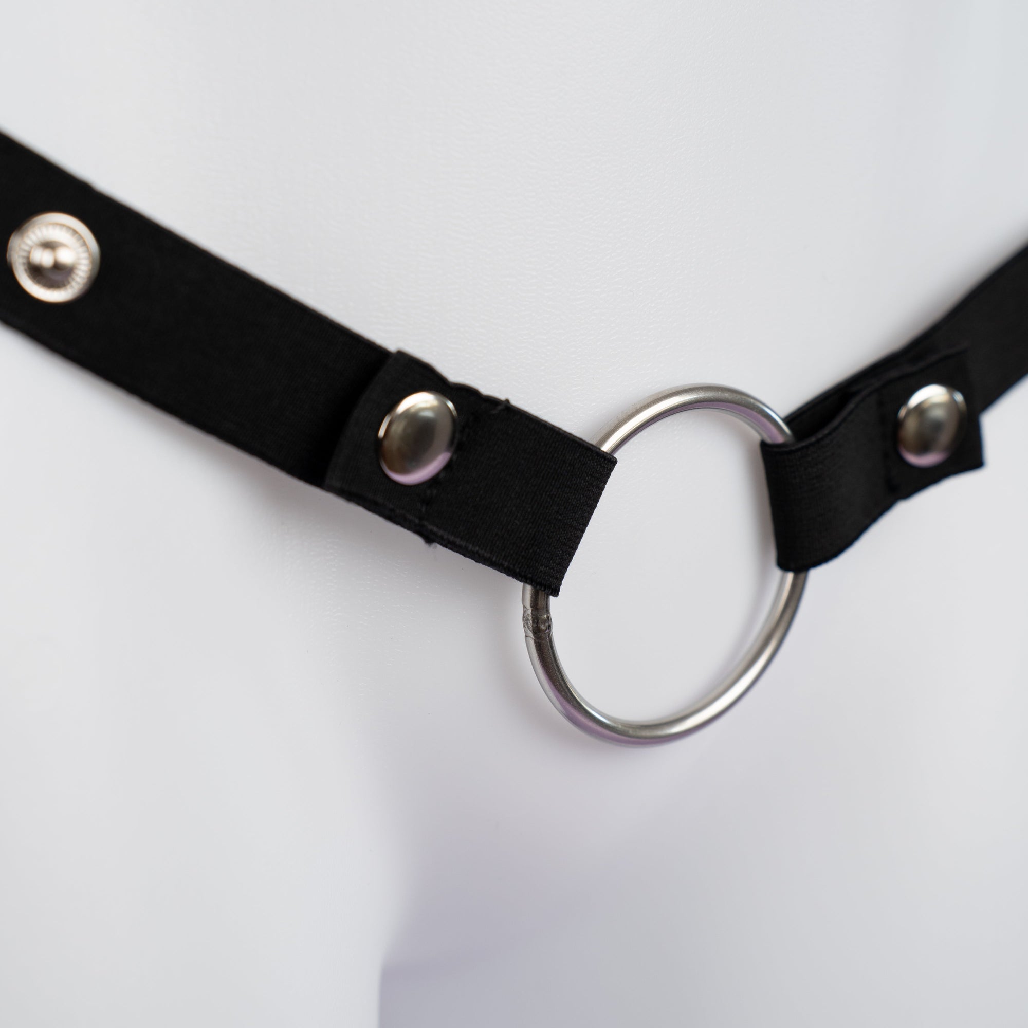 Close up of the black elasticated chastity belt showing ring and adjustable size options.