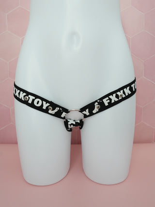 The black and white chastity belt is shown on a model in front of a pink background