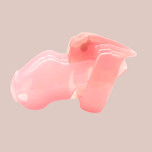 Shown is the pink small cock cage that we offer in our version of the Holy Trainer range. It is shown from the side angle so that you have a full view of the assembled chastity cage, the cock cage is shown attached to a base ring and the integral lock is in place, showing how it fits to the body. This product is the pink version, these cages also come in black and clear.