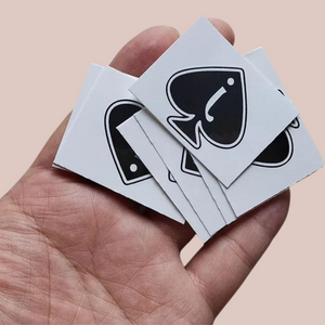 Showing a pile of Jack Of Spade temporary tattoos, it shows a black spade with a lowercase i in the centre.