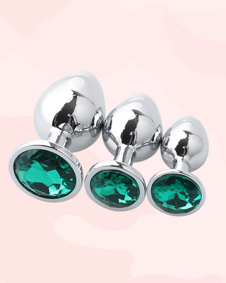 Three metallic anal plugs in small, medium and large, with green gemstones