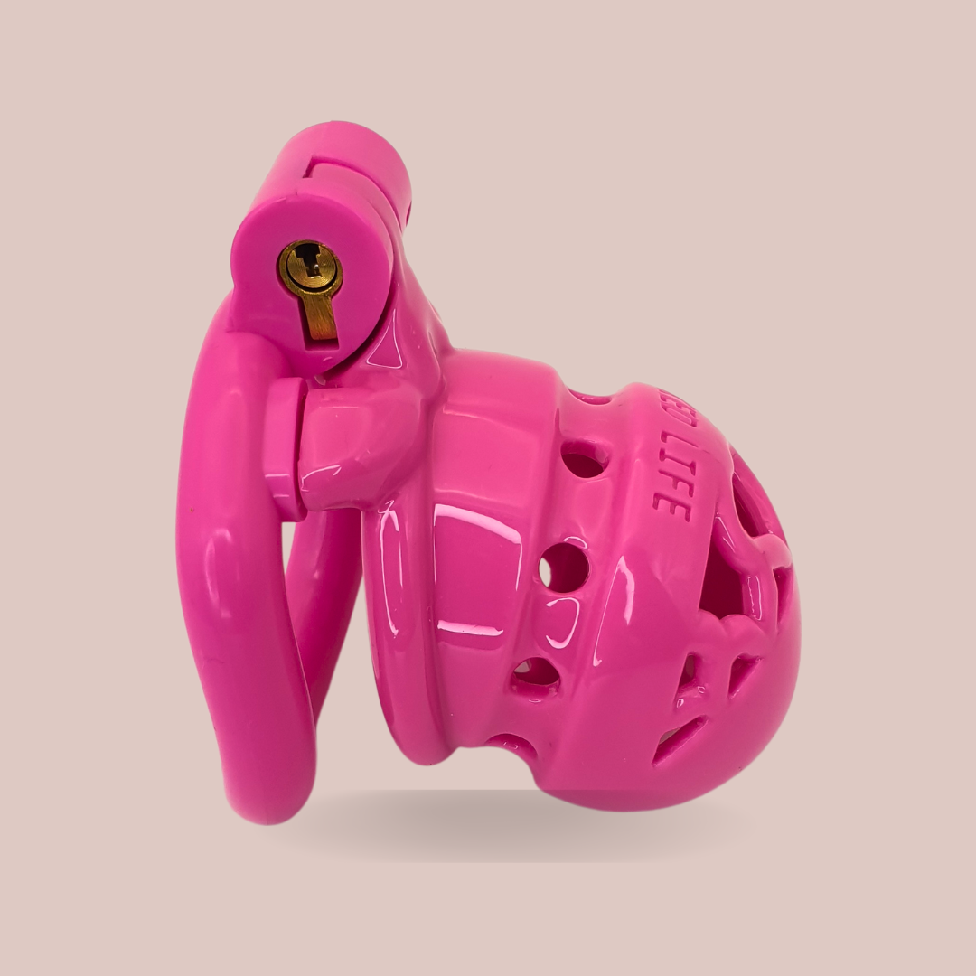 A side view of the pink Locked In Love Chastity Cage from House Of Chastity with the worlds LOCKED LIFE engraved across the front, it is shown here fully assembled with its base ring and integral lock.