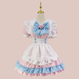 A front view of The Lucy Lou, its a frilly layered pink pinafore style sissy dress. You can see the under dress with peter pan collar, detachable paw print brooch and bow, pinafore style apron and white frilled head band.