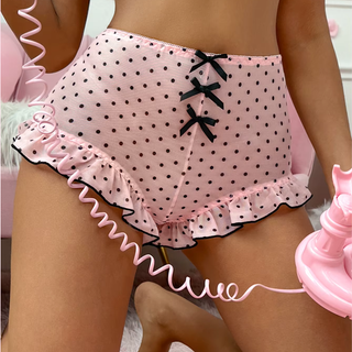 Pink polka dot panties with a ruffled hem and black trim, shown on a model.