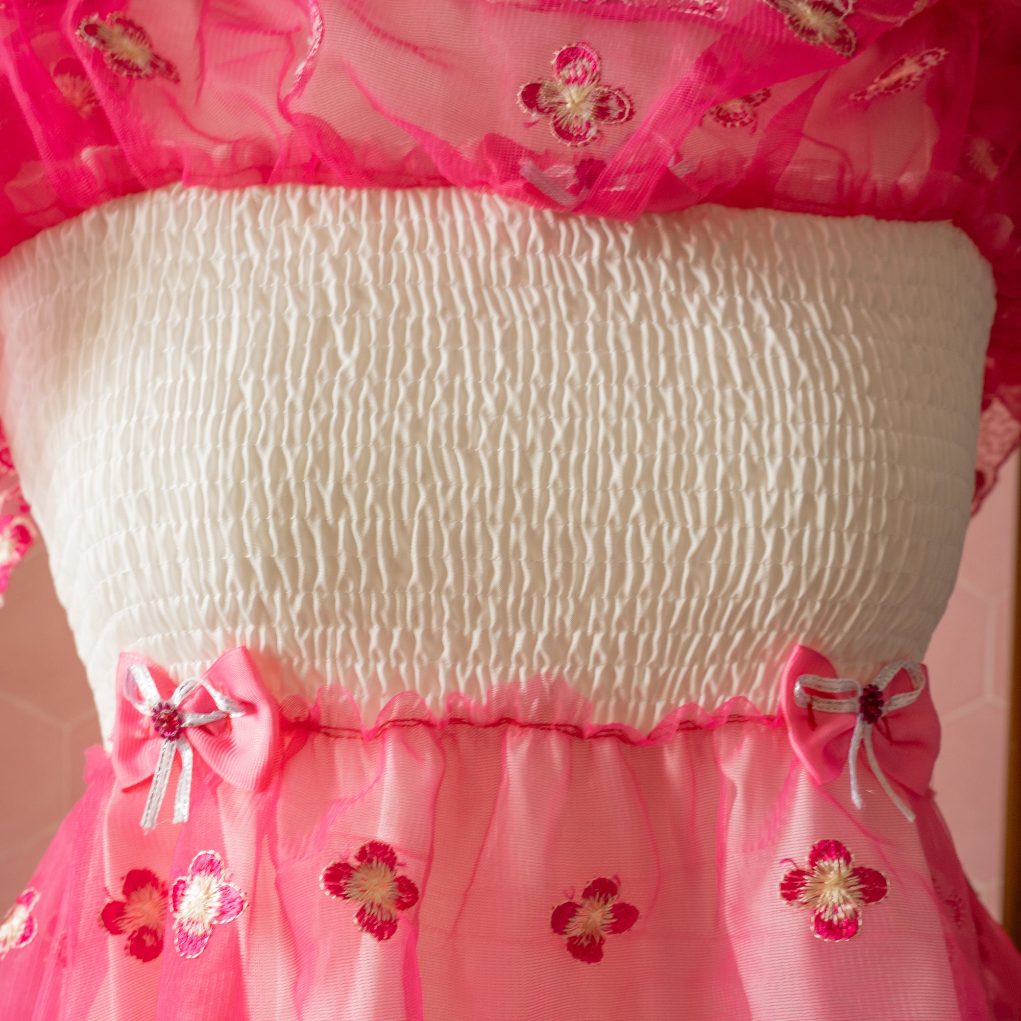 The top sheer layer has been lifted to show the white stretch bodice, and decorative bows to the waist.