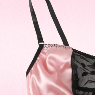 A close up of the satin and polka dot mesh fabric on the bra, shown on a pink background