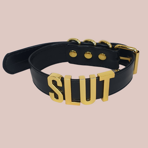 A close up of the black Slut collar with gold lettering. 