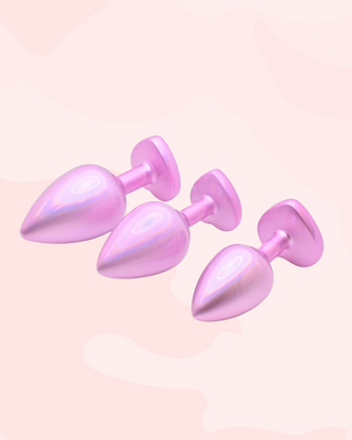 The small, medium, and large butt plugs can be seen from an alternate angle, the pink pearl colouring covers the whole surface of the plug, including the heart end.