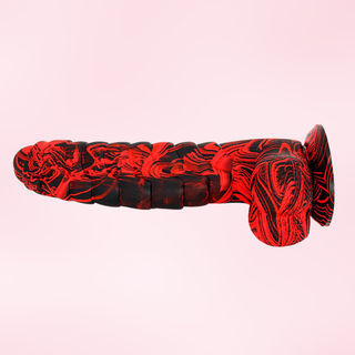 A side view of the mottled red/black Wyvern Whisper dildo, the suction cup base can be seen.