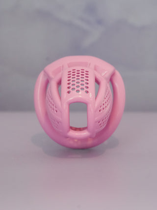 The pink chastity cage is shown from the front, the cut outs allow for airflow.