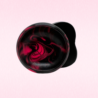The base of the suction cup of the Emberkiss sho9wn against a pink background