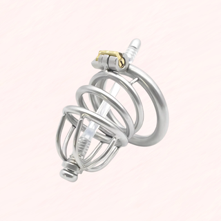 A view of the fully assembled Lock Up Chastity Cage with silicone urethral tue on a soft pink background