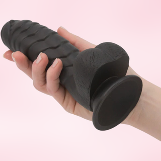 The black Wyvern Whisper Dildo in black being held in a hand.