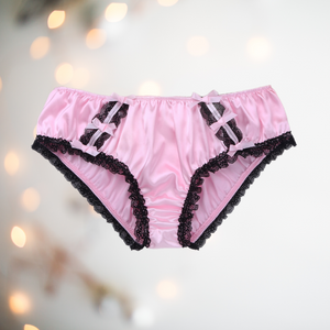 Shown unworn, Adult knickers for men, sissy, lgbt, unisex. Made in pink satin with black lace detailing to the legs and panels on each side. There are also matching pink satin bows prettily applied.