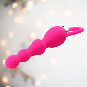 a bright pink beaded anal sex toy, shown lying down.