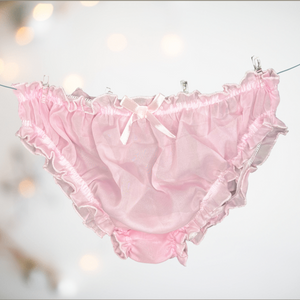 A close up of the soft pink see through bikini shaped panties for men, you can see the elasticated waist and legs, and the decorative matching pink bow. 