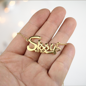 A close up of the gold Sissy necklace on a hand, it is shown  with xoxo beneath and hearts at the end.