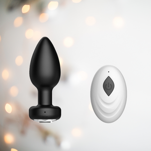 The black vibrating butt plug shows its jeweled base and the small remote control that comes with it.